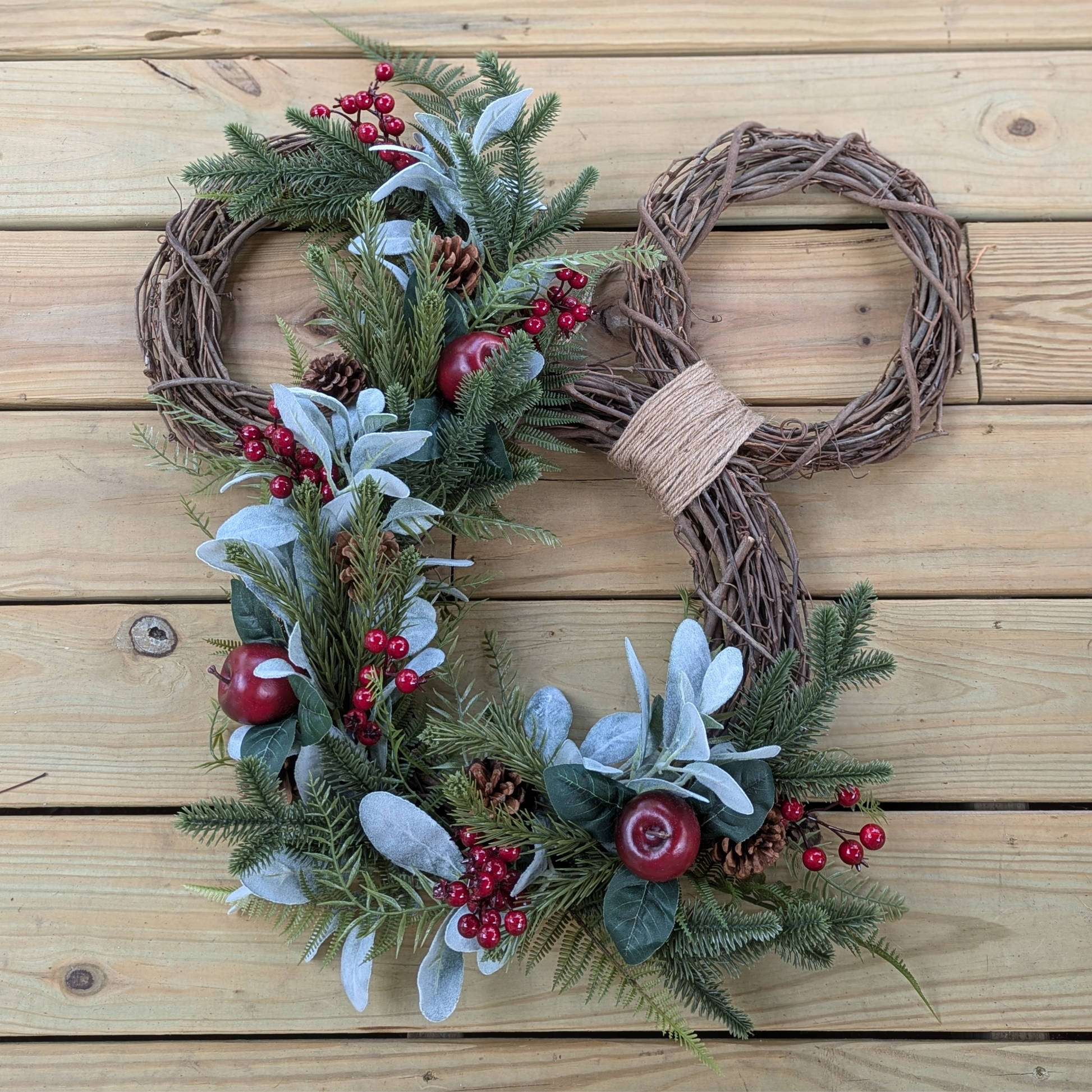 A festive Christmas wreath crafted in the shape of Mickey Mouse's head, adorned with green artificial foliage, red berries, and beautiful faux lambs ear
