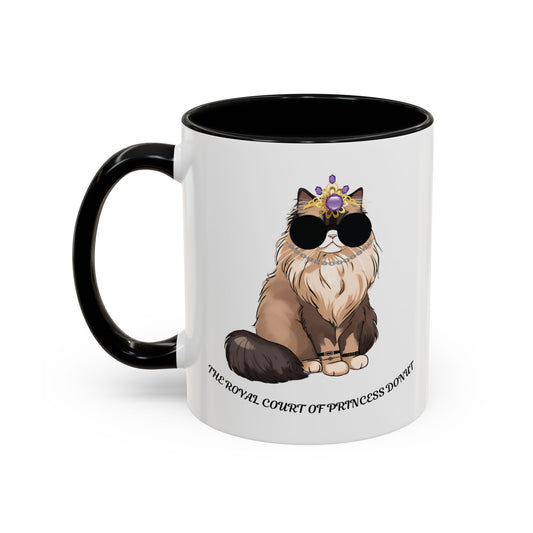 A white ceramic coffee mug with a quirky illustration of a character resembling a donut with a crown and sunglasses, and the text 'The Royal Court of Princess Donut'.
